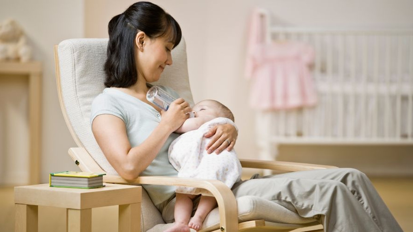 A mum feeding her baby in a nursery rocking chair