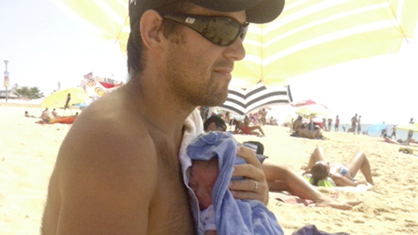 Ben cradles his tiny son on an Algarve beach
