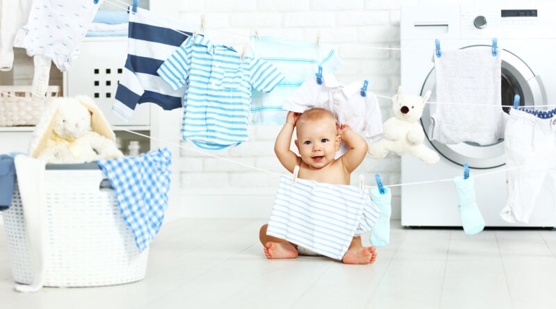 A baby sitting in front of a line of laundry