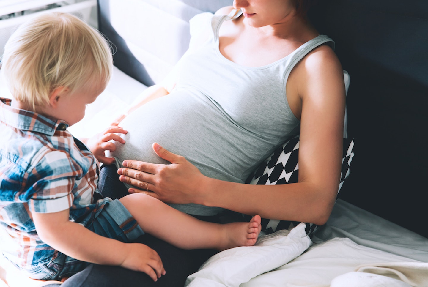 Toddler touching mum's tummy