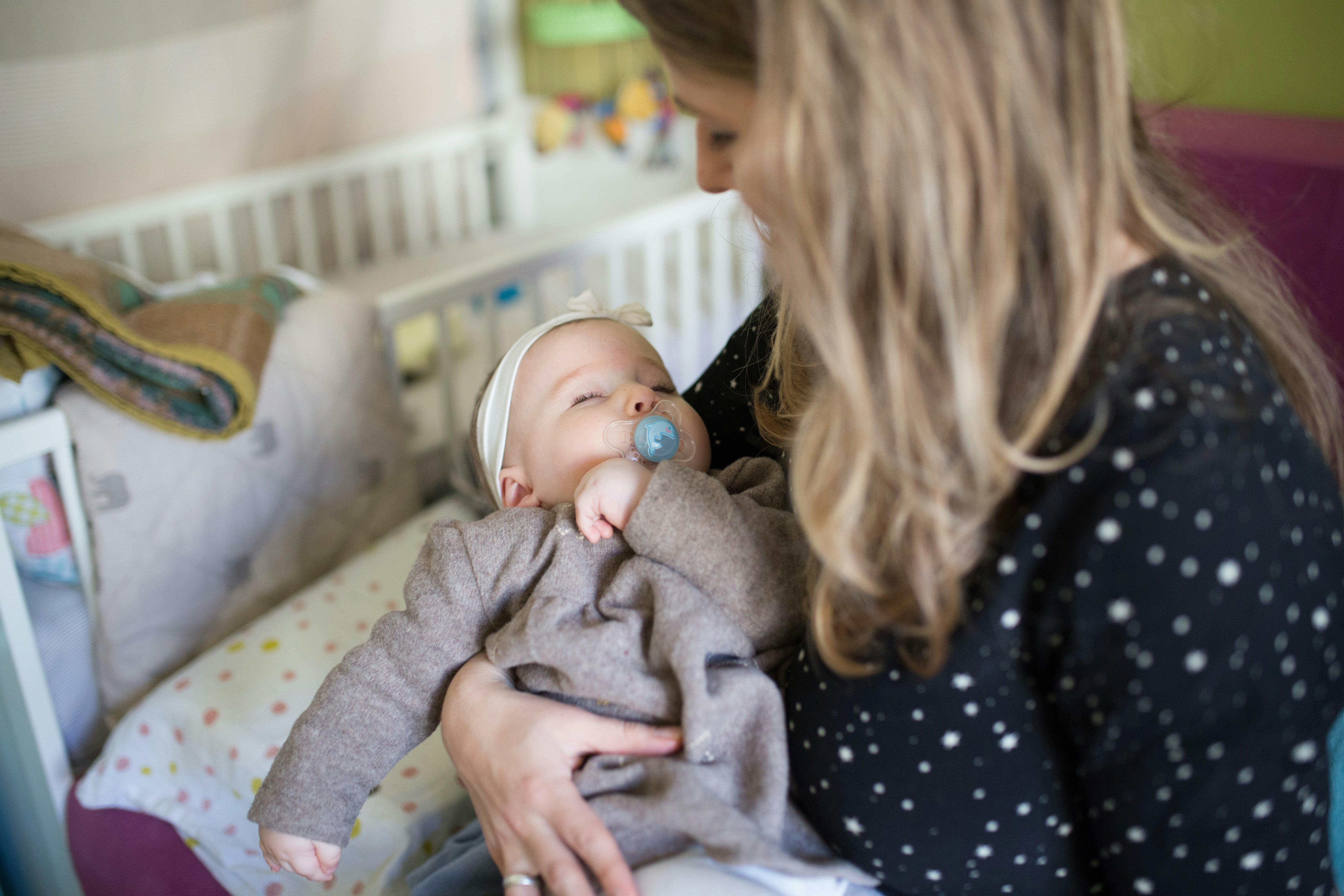 Mother cuddling her baby who is being soothed with a dummy