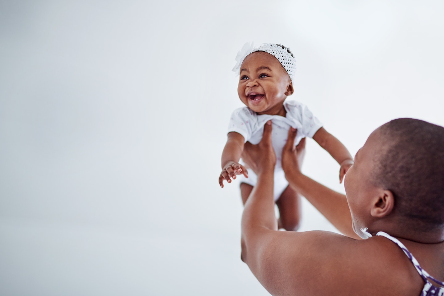 Newborn baby smiling, being help in air