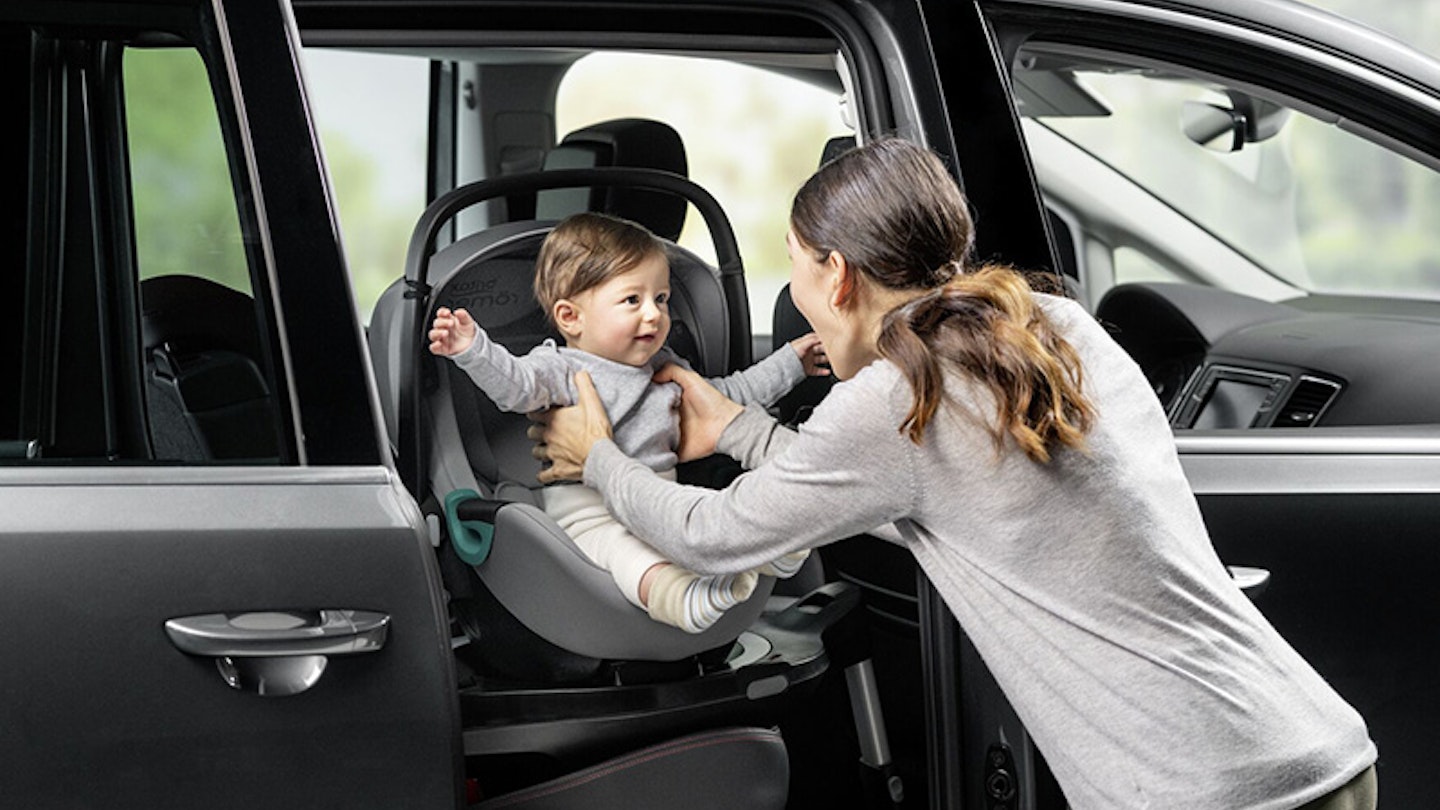 A woman placing her baby in a car seat