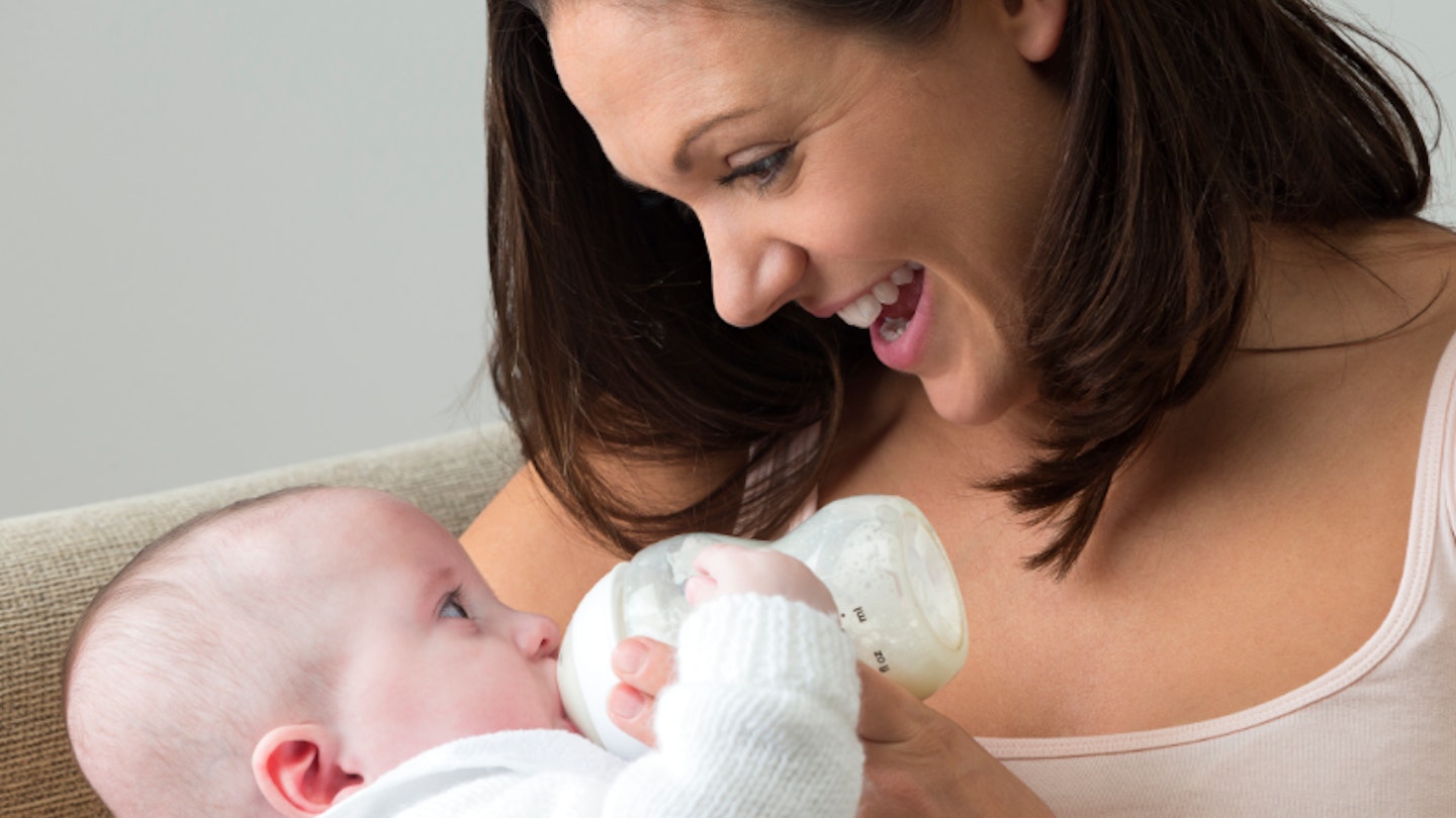 Mother bottle feeding top baby