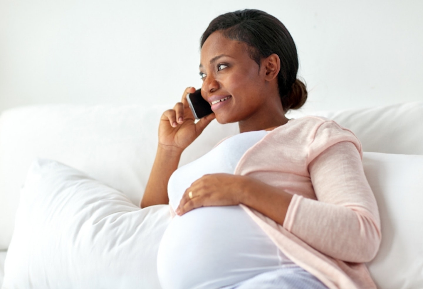 Pregnant woman sitting on a sofa on the phone