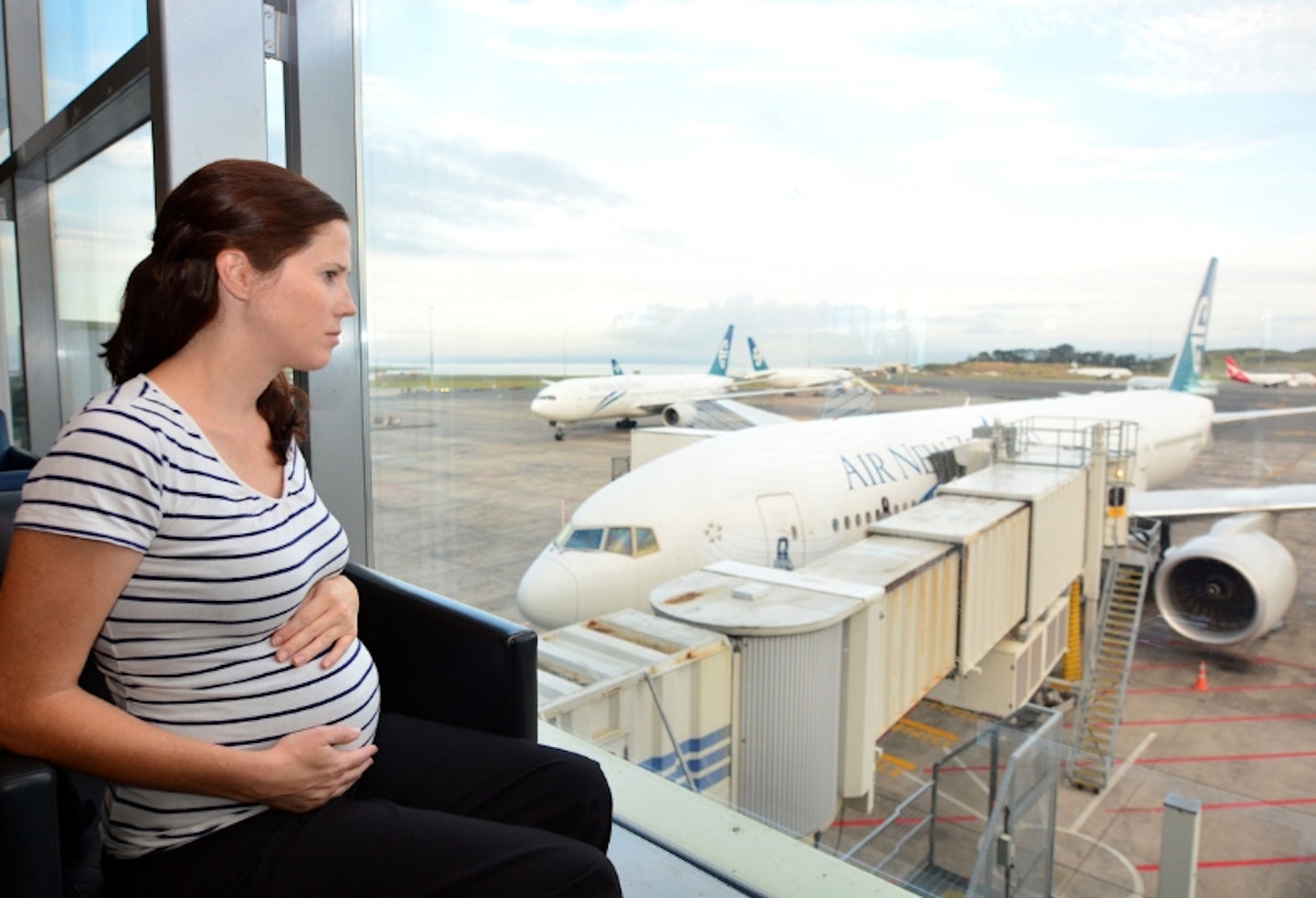 Pregnant woman at airport looking at planes
