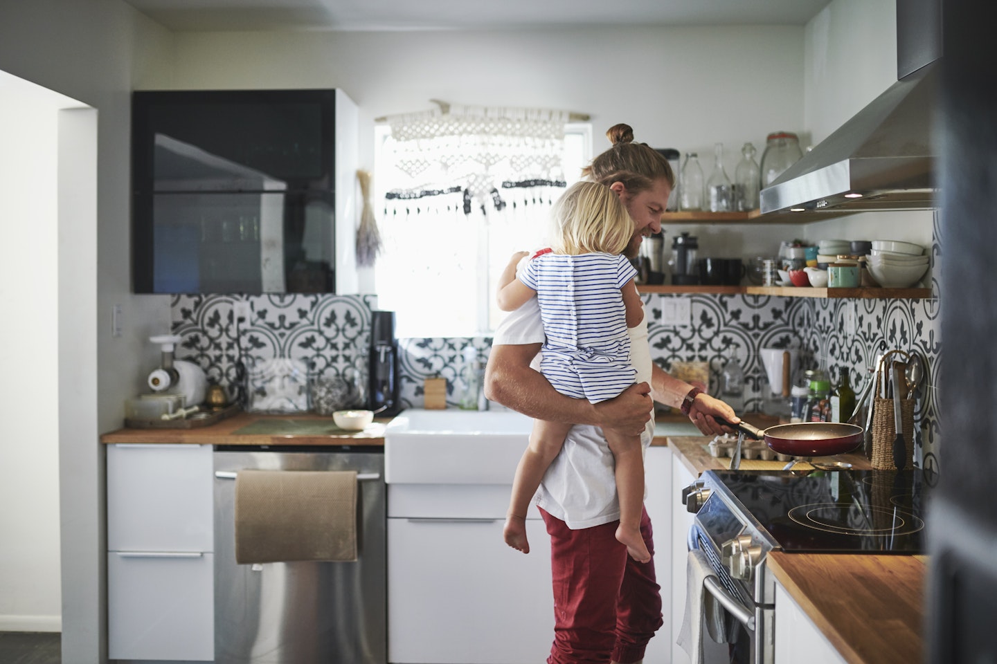 dad cooking whilst holding his daughter