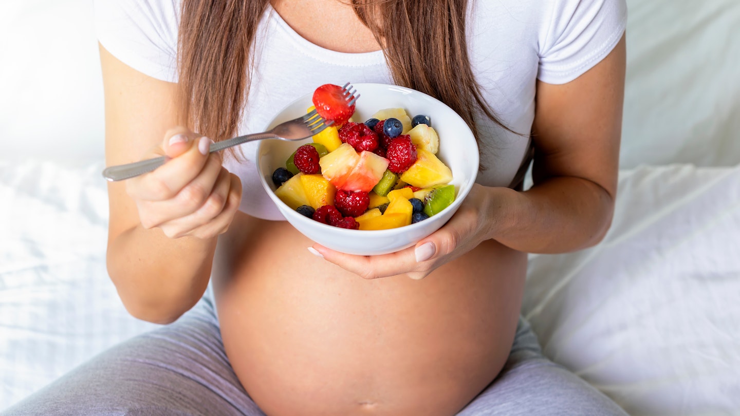 Pregnant woman eating fruit 