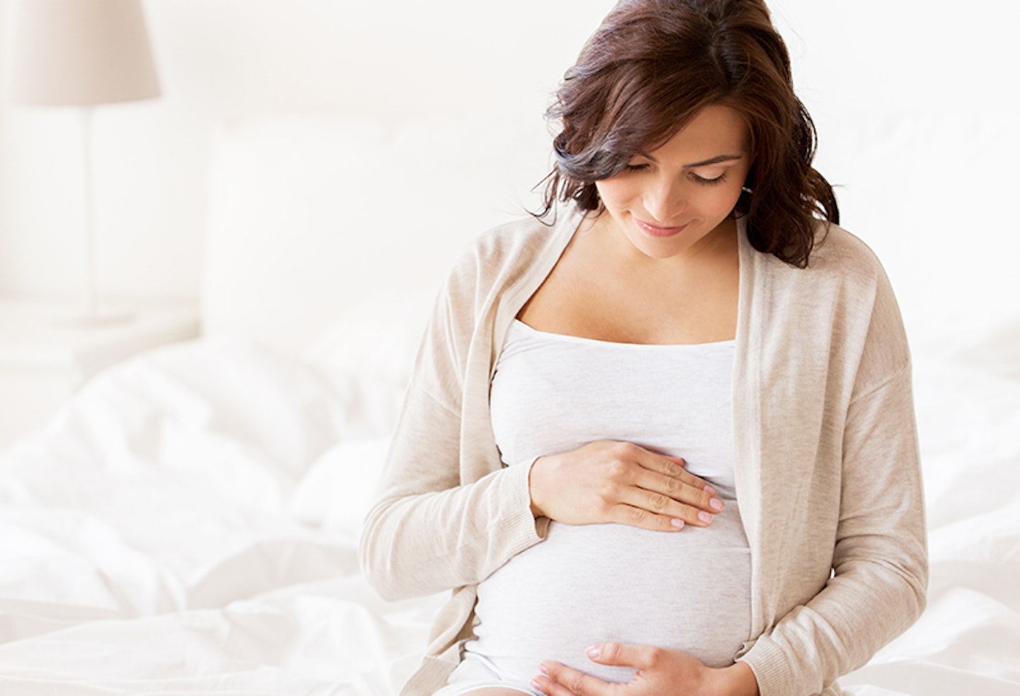 Pregnant woman holding her bump and looking down lovingly