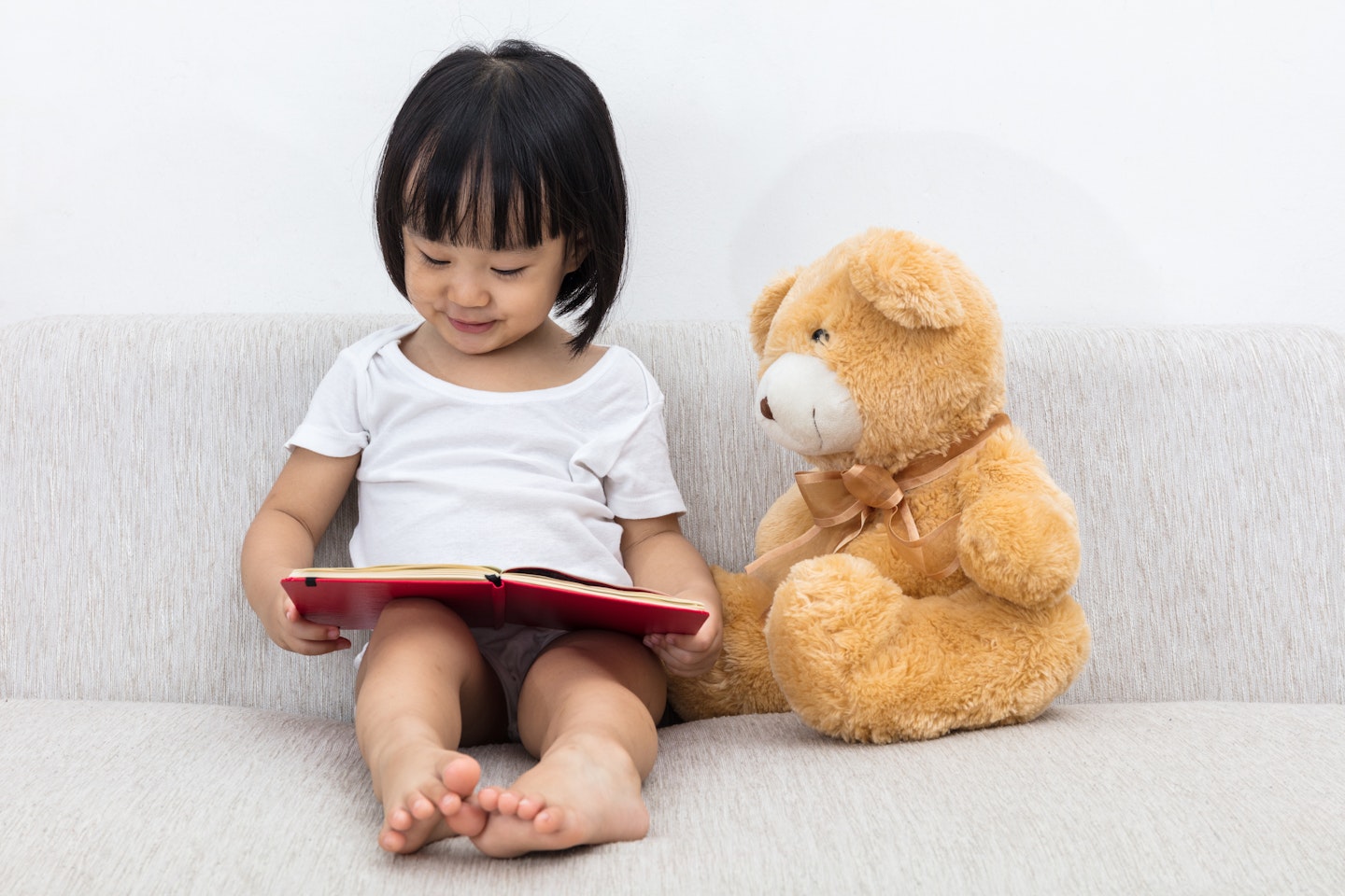little girl reading with teddy