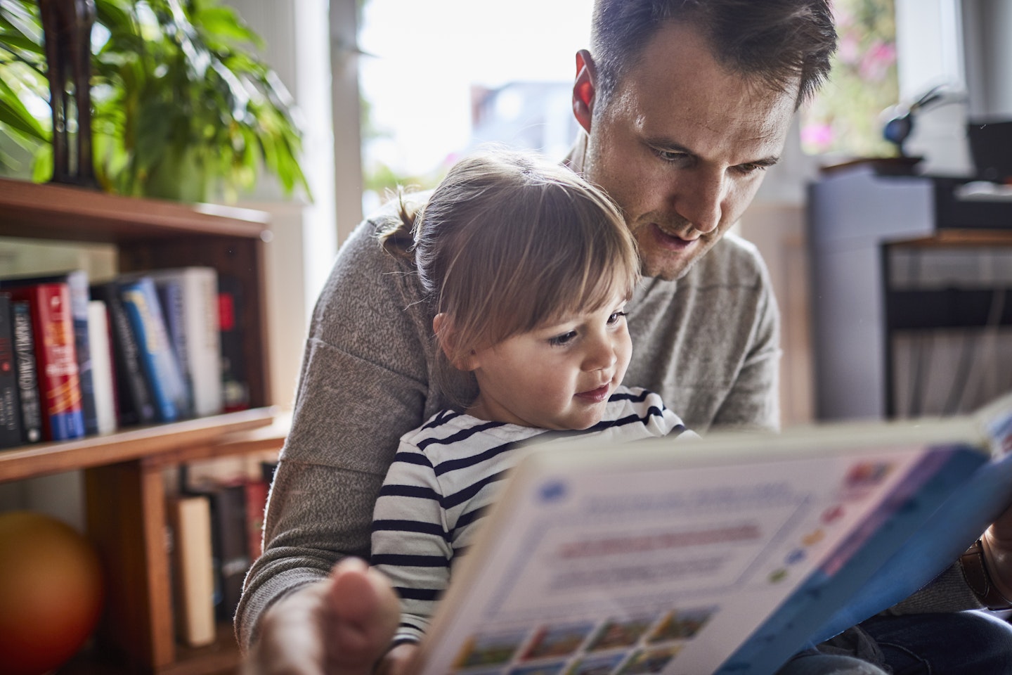 Father and daughter enjoying a book together which is both educational and calming.