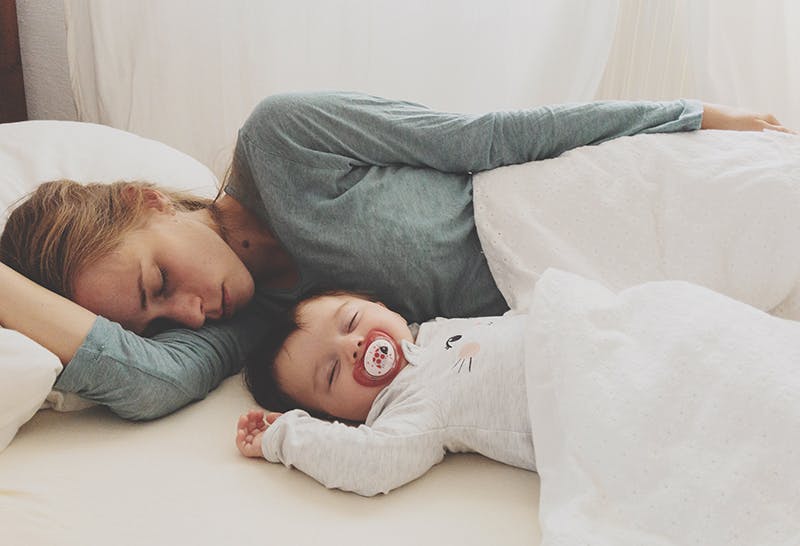 Mom sleeping with baby in outlet crib