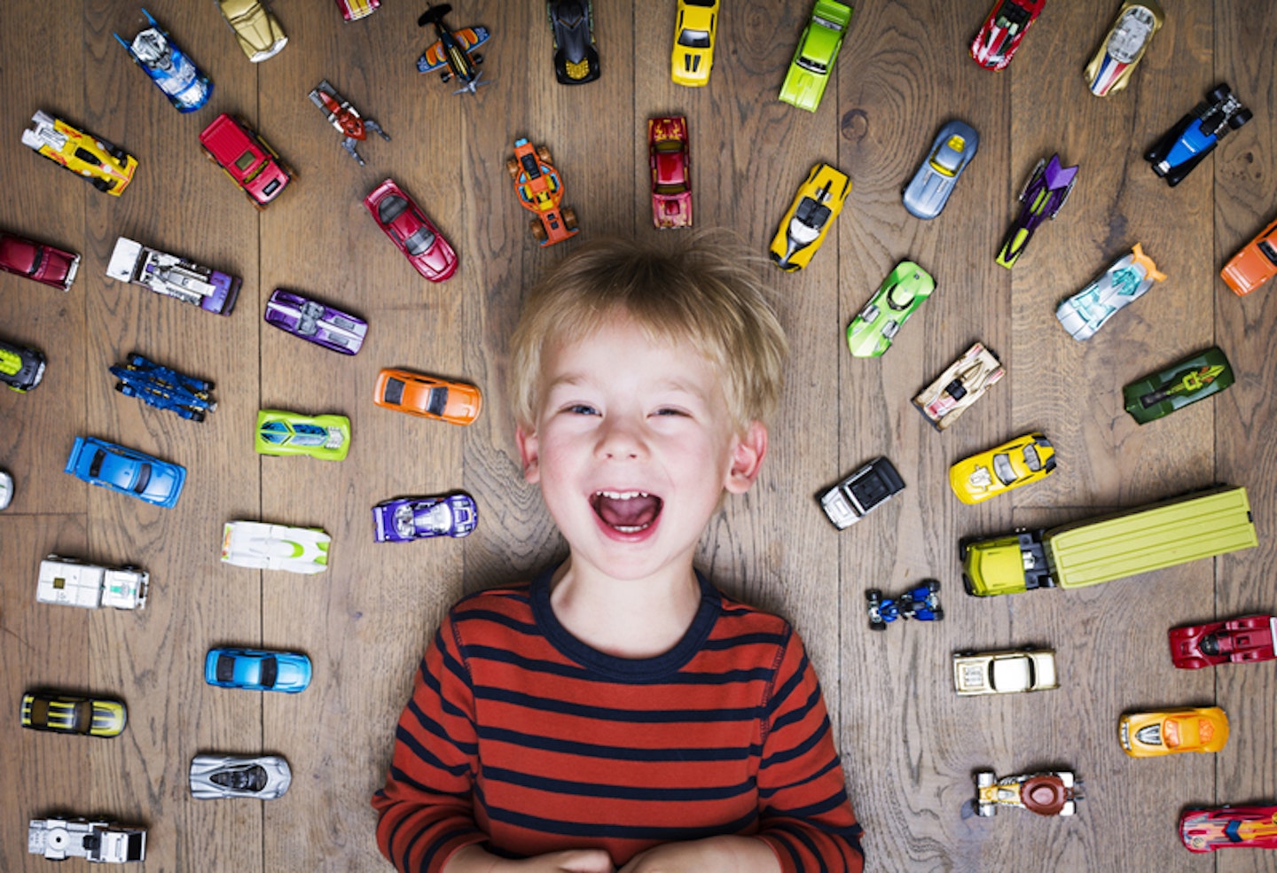 toddler with cars around him