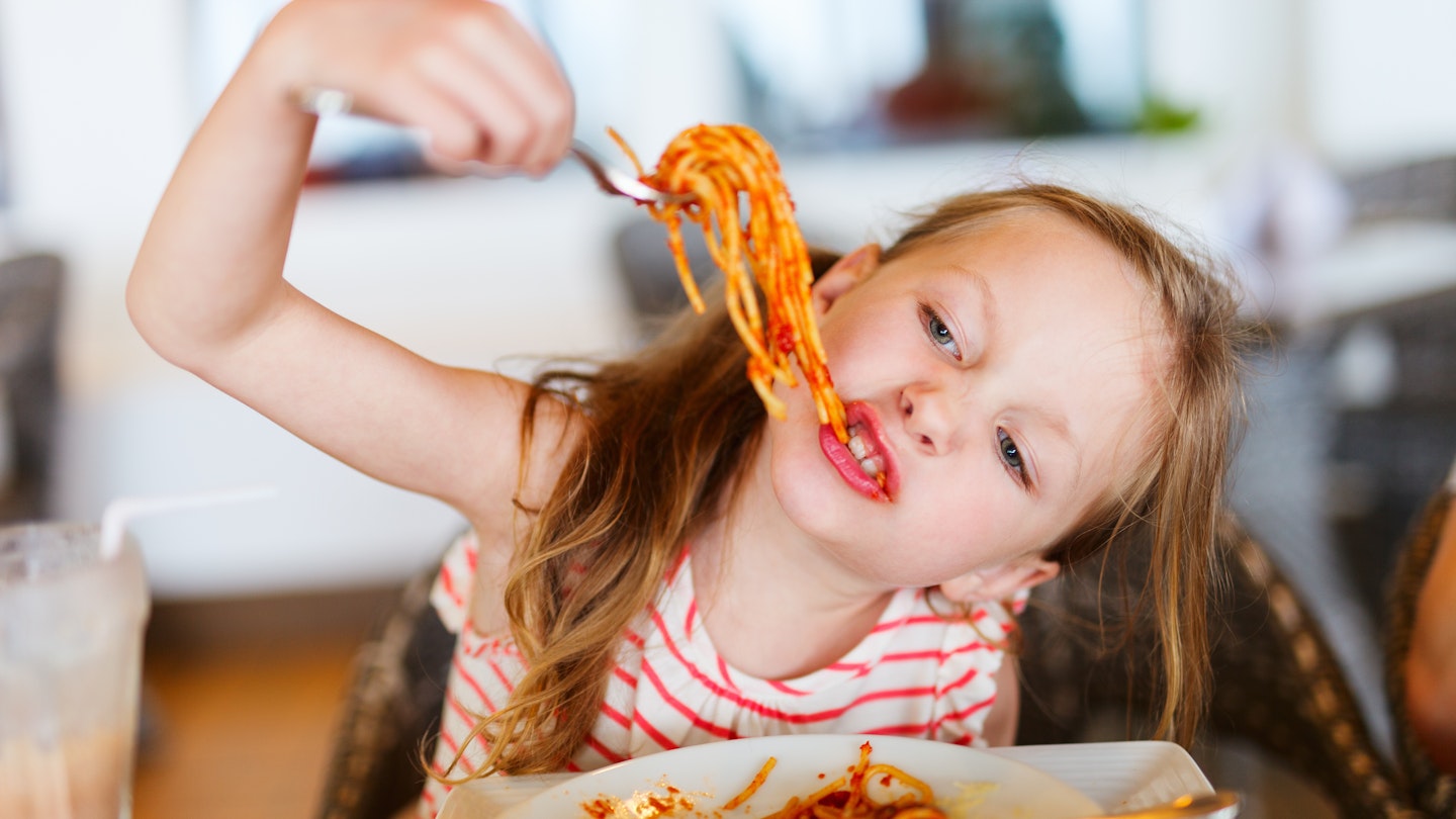 Young girl eats pasta