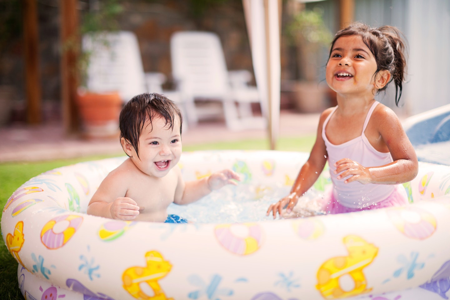 siblings playing in a paddling pool