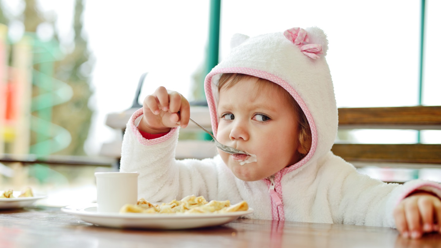 Toddler girl eating in restaurant 