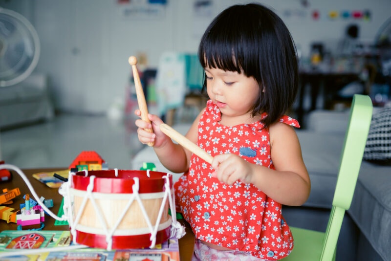 A little Chinese girl playing with a toy drum