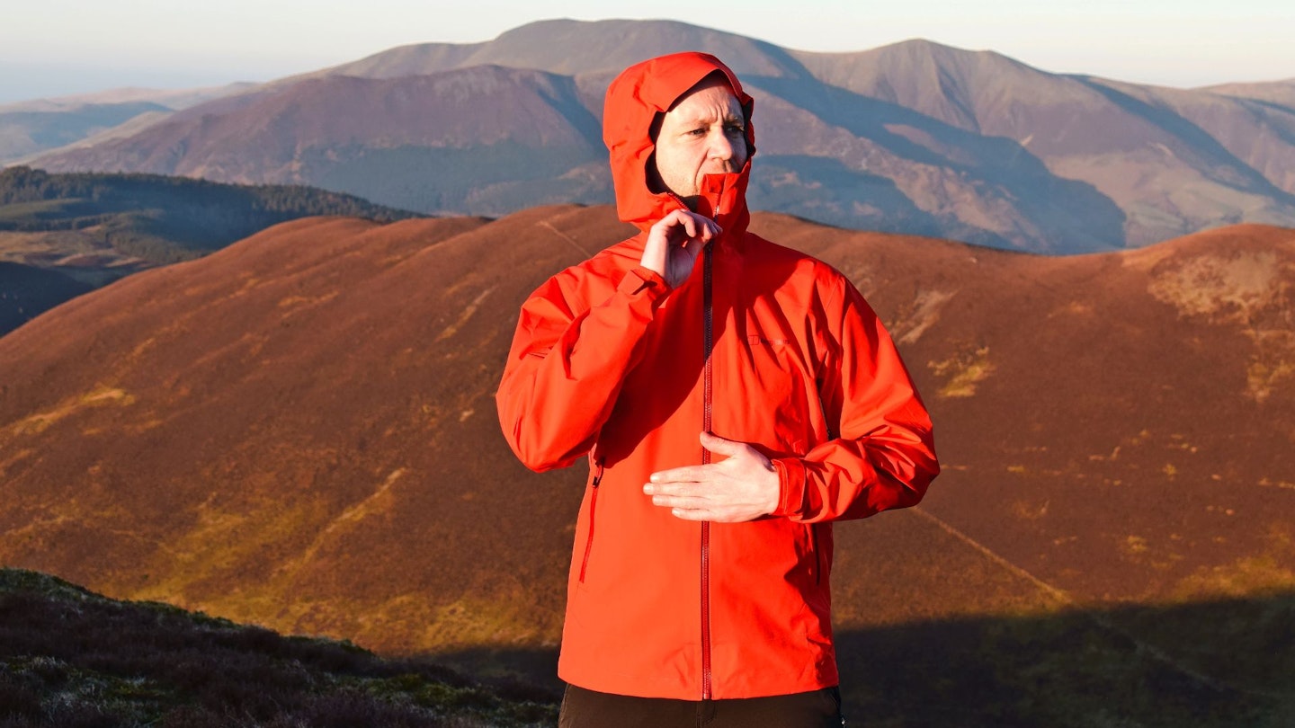 Male hiker wearing an orange waterproof jacket