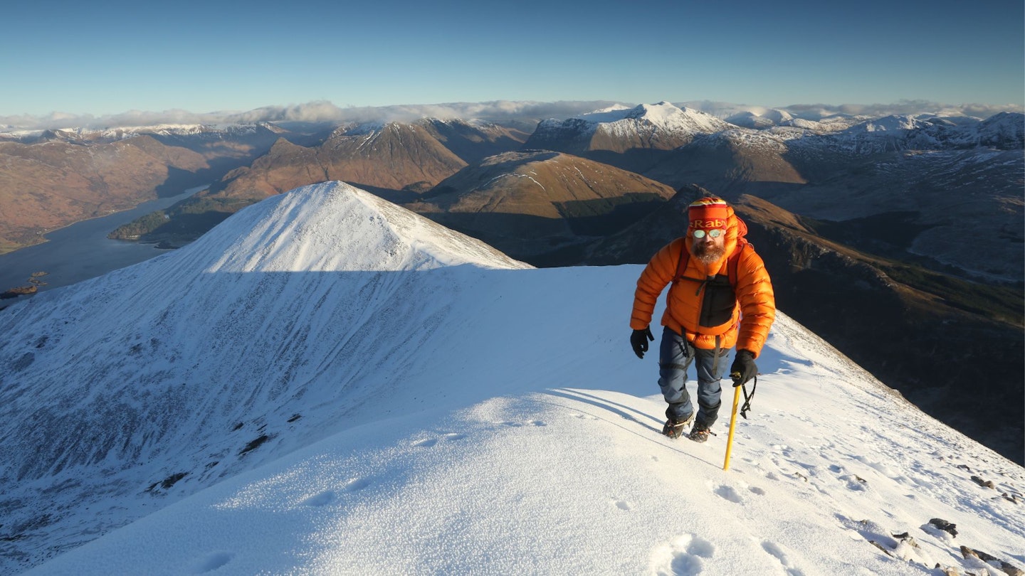 Hiker near the top of a winter mountain in a down jacket Scottish Highlands