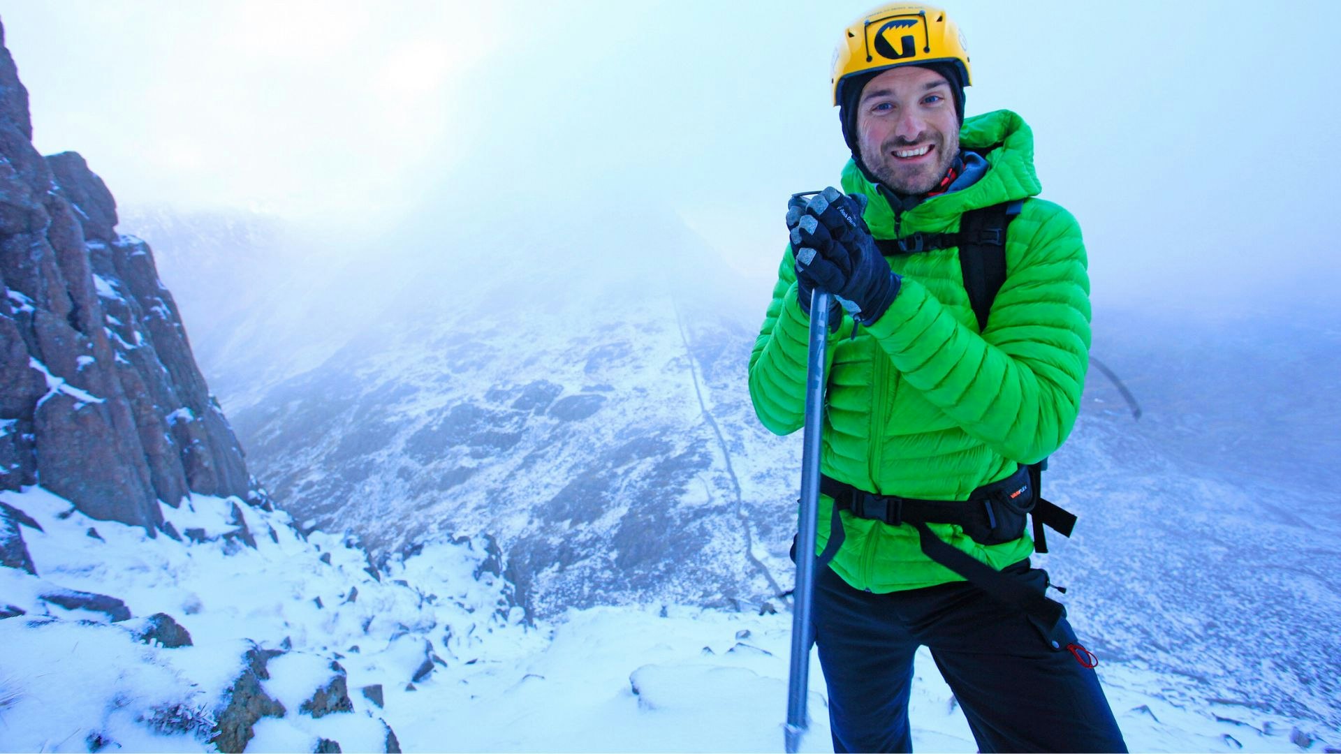 Hiker in snowy Bristly Ridge, Snowdonia wearing a green down jacket