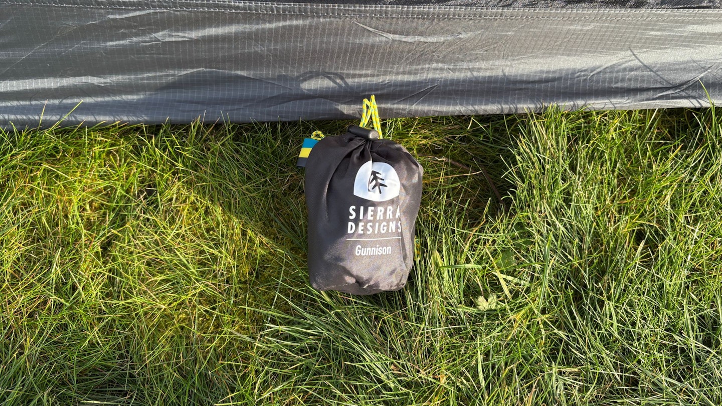 An image of the Sierra Designs Gunnison Pillow packed into its bag outside a tent