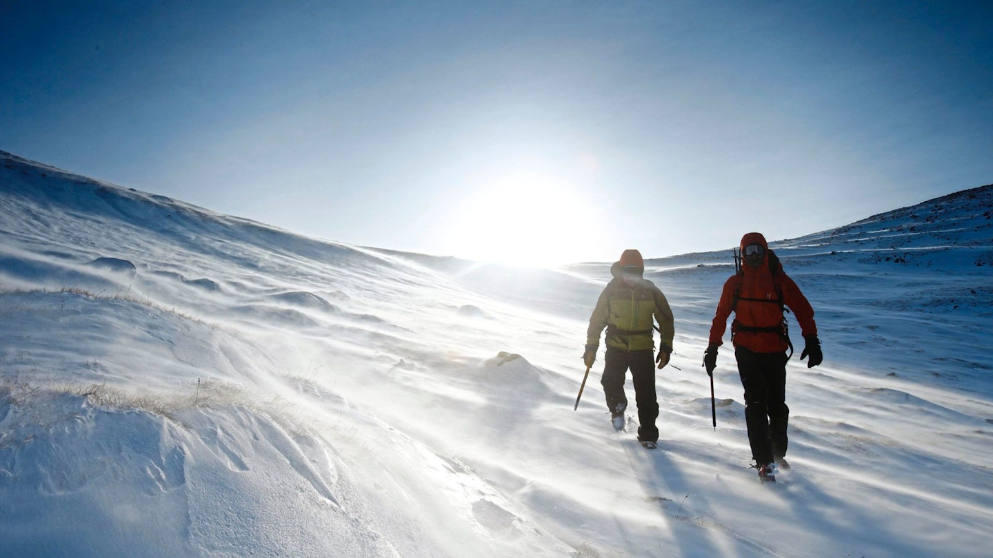 Two hikers walking up a snow-covered hill