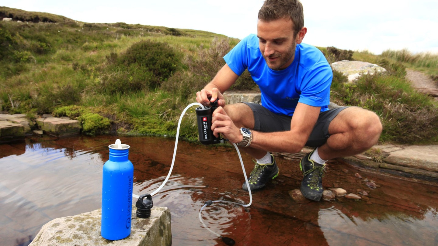 Hiker using a water filter in a stream