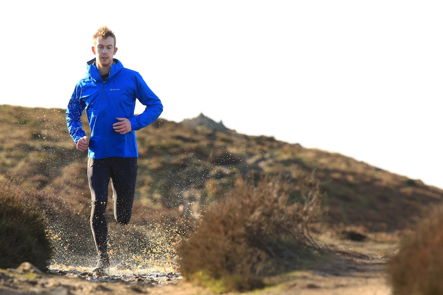 Male runner in winter going through a puddle