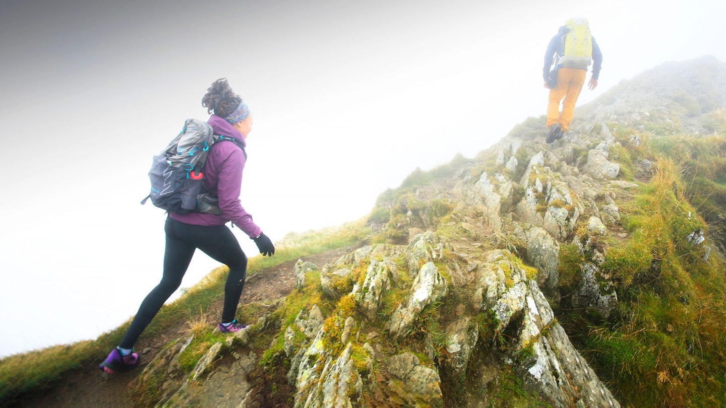 Two hikers climbing a hill wearing budget waterproof jackets