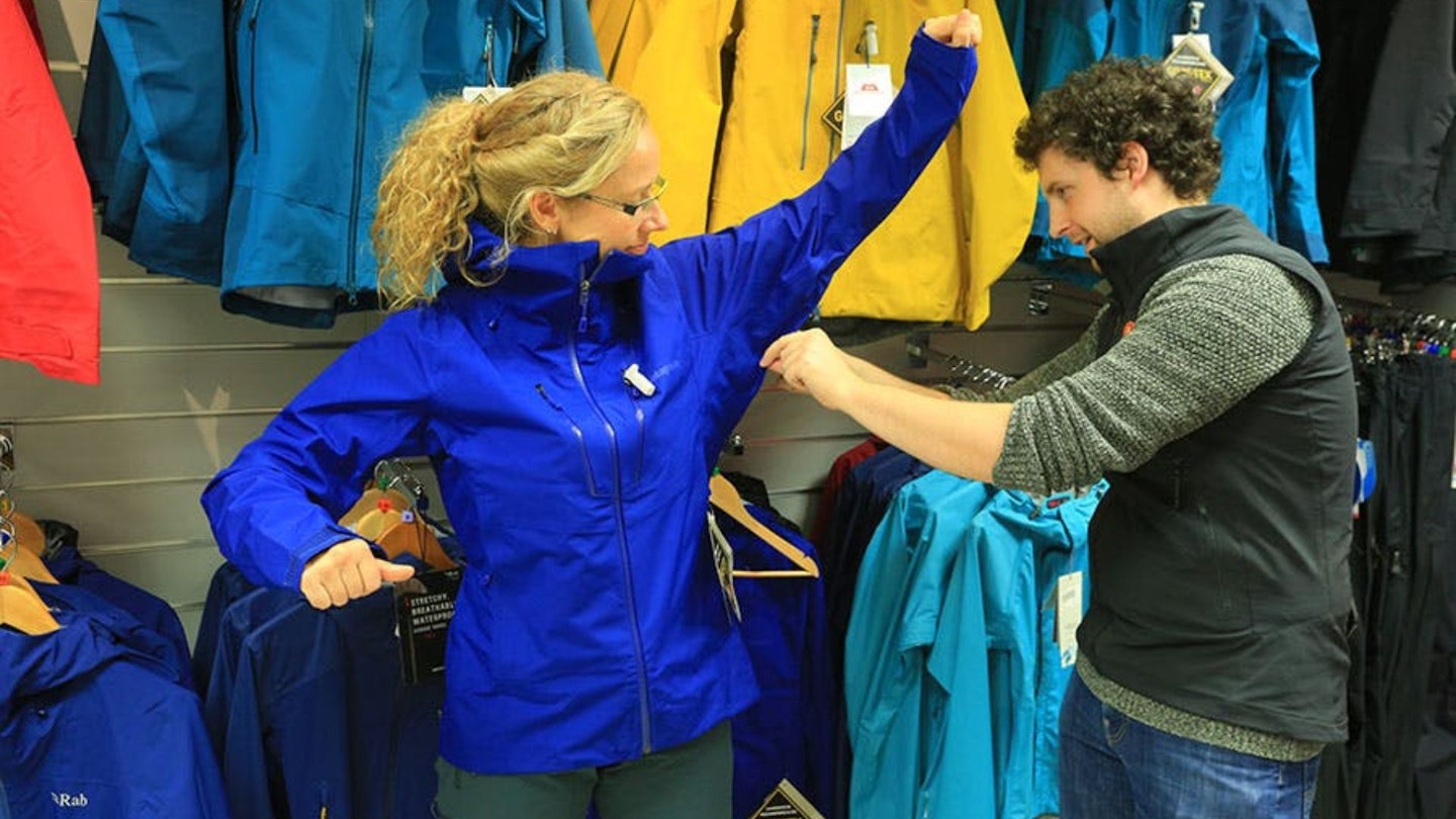 Woman trying waterproof jacket in gear shop