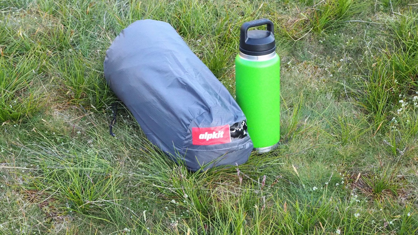 Packed away tent next to a drink bottle