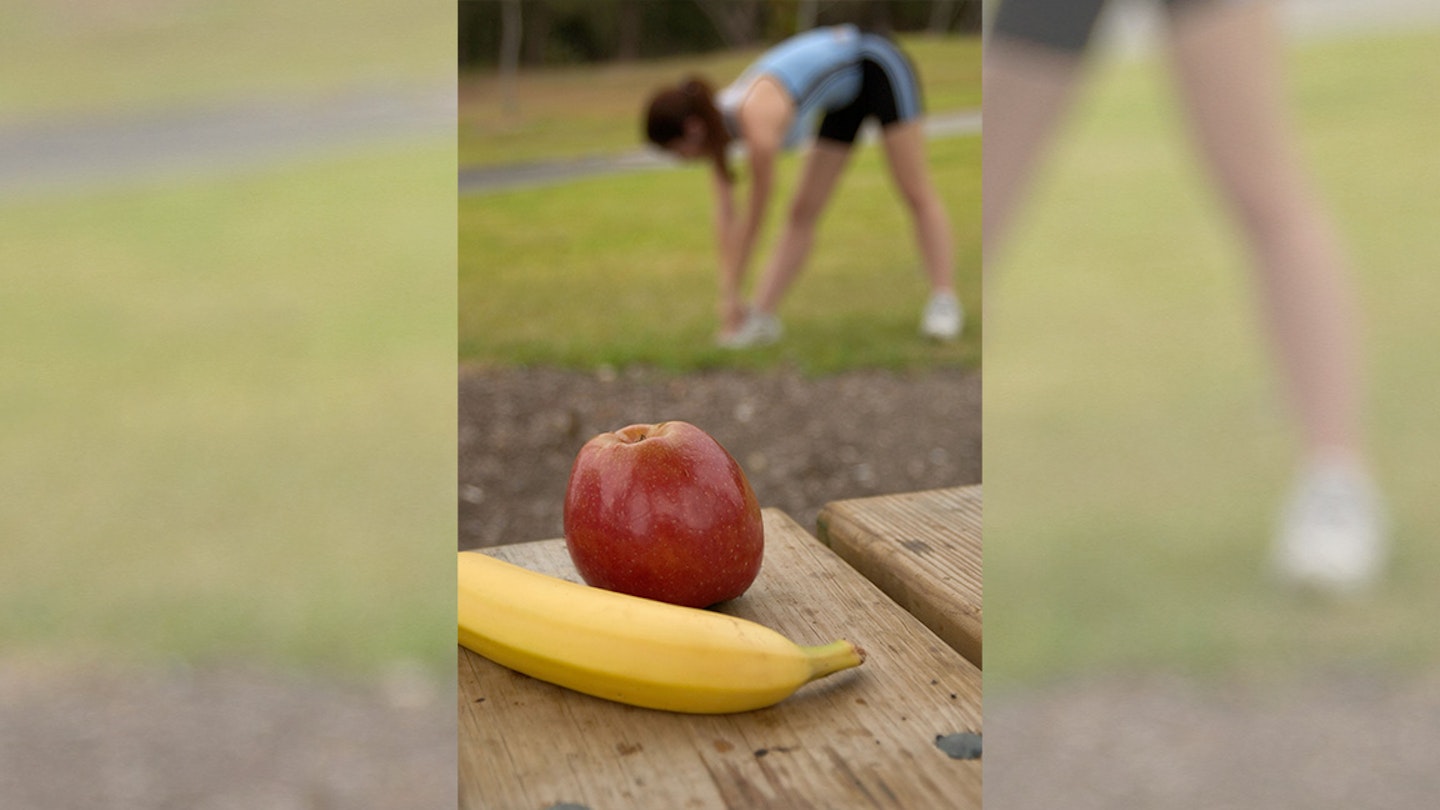 woman stretches with fruit in the background