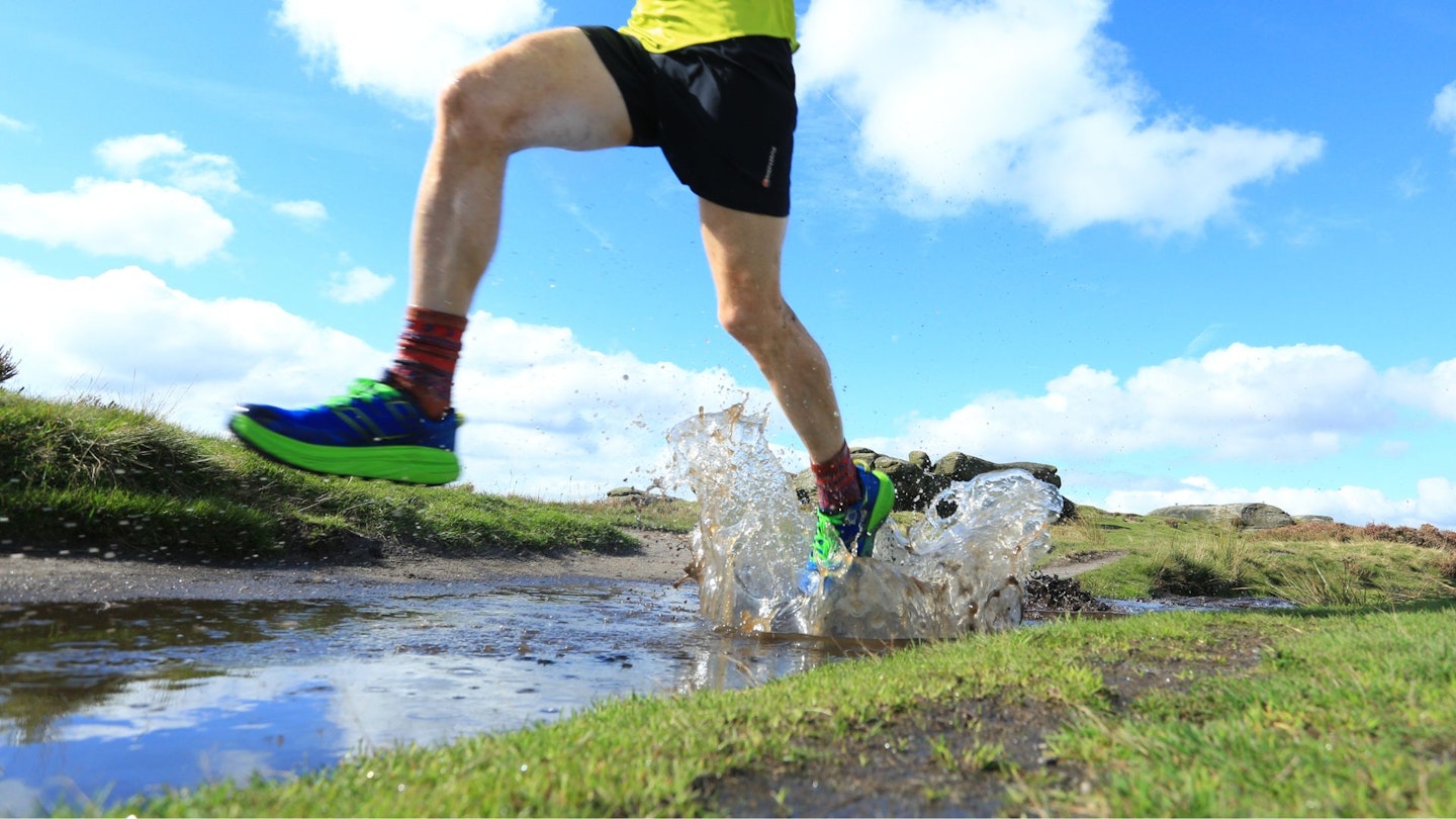 Marcus Scotney running through a puddle wearing waterproof trail running shoes