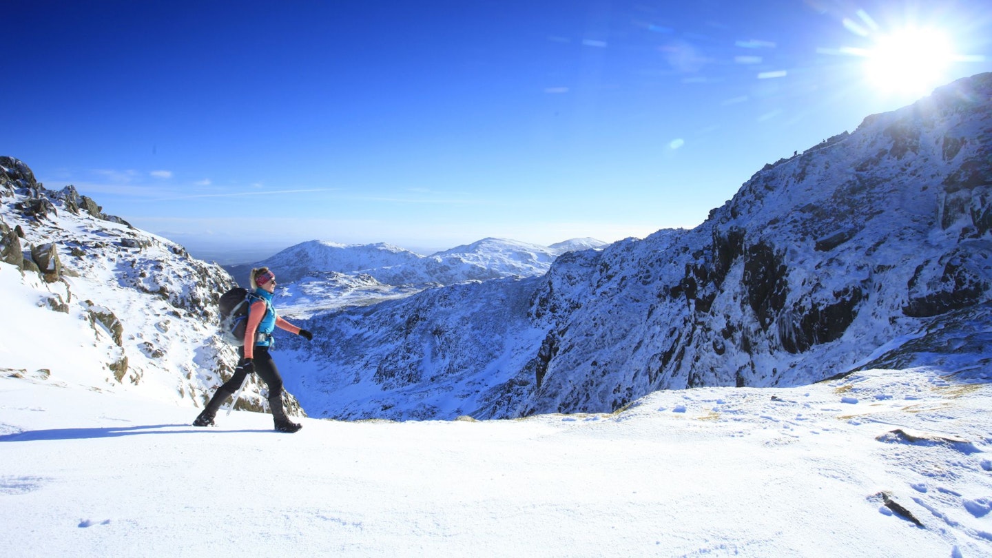 Hiker walking snowy Crinkle Crags, Lake District