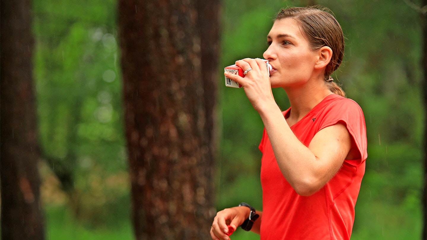 a runner takes a drink in the forest