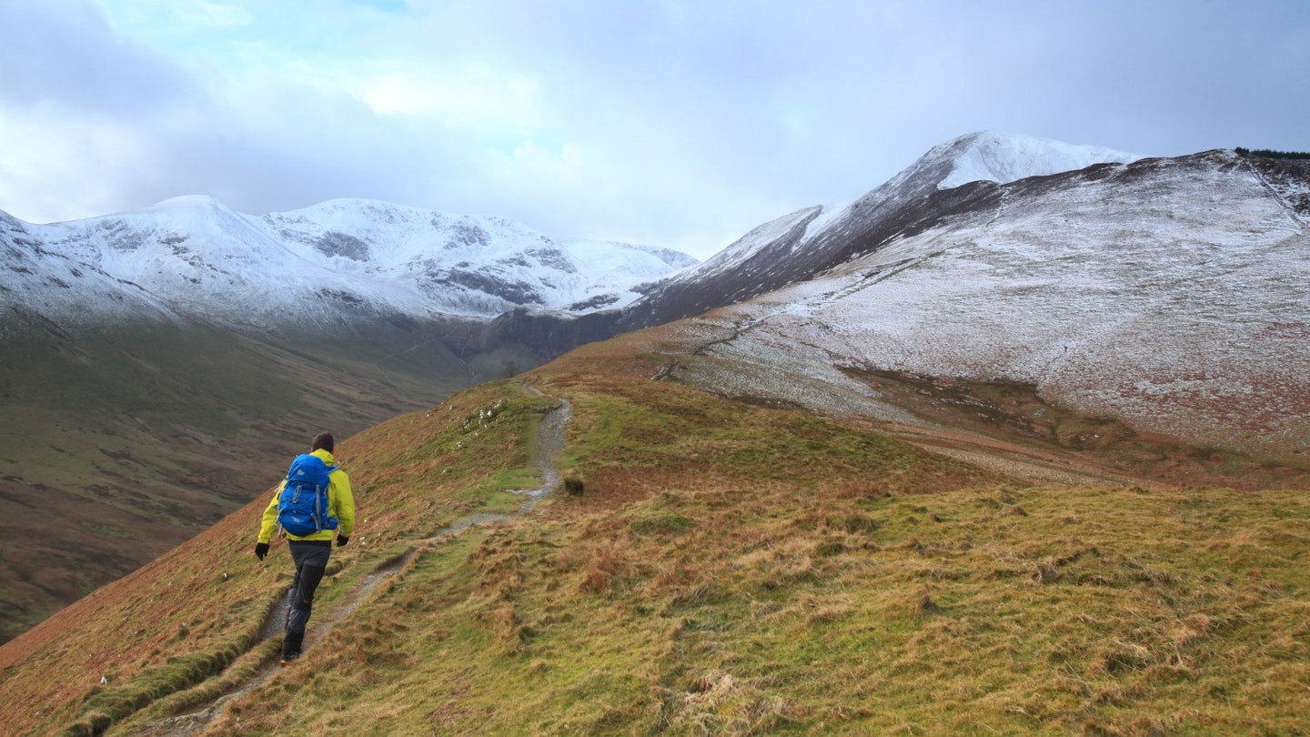 Hiker climbing up Grisedale Pike in winter