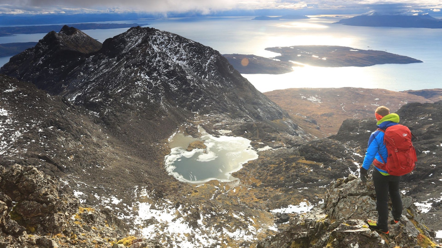 Hiker looking over Loch Coire a Ghrunnda from the summit of Sgurr Alasdair