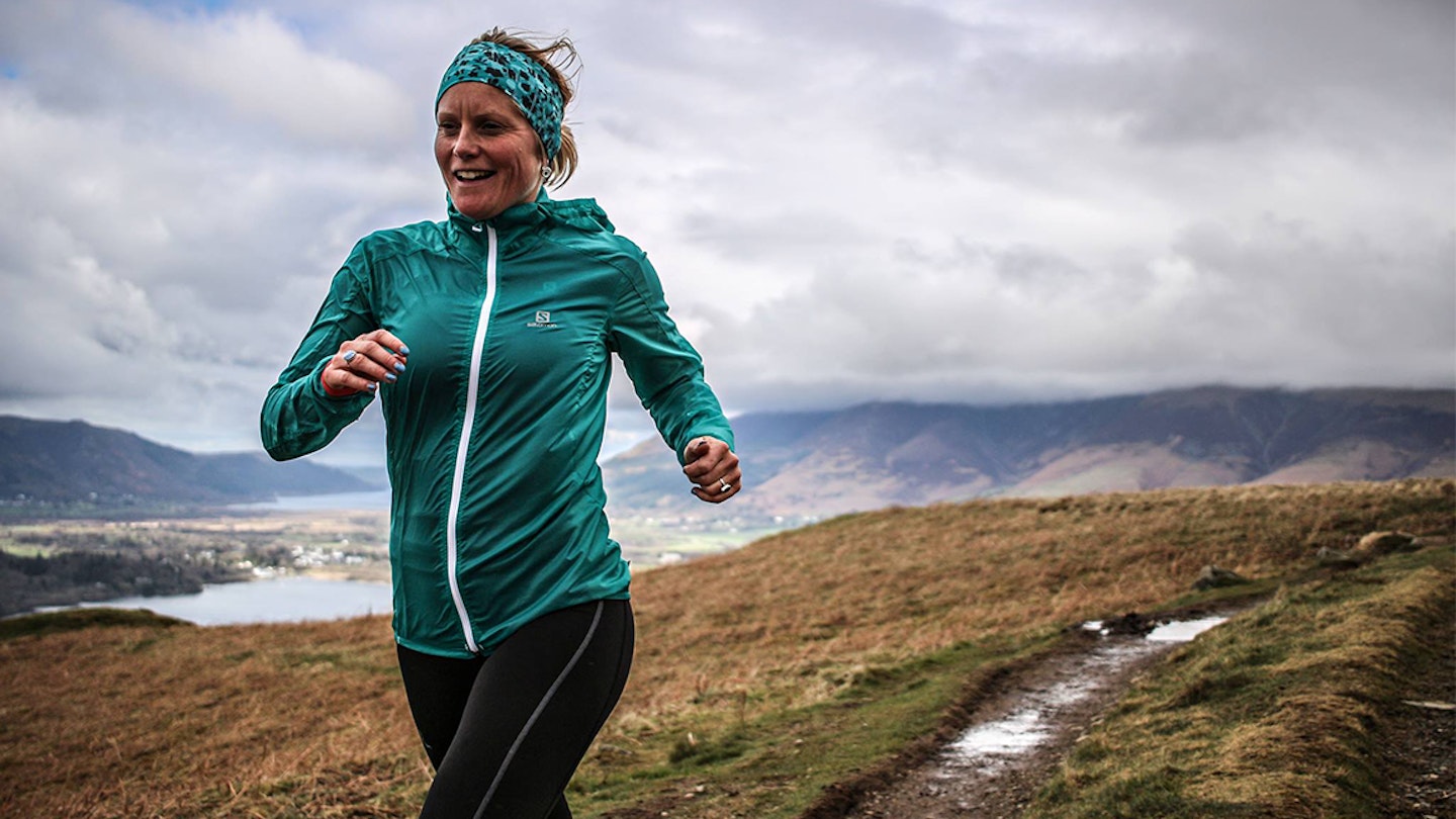 woman runs along some fells with a smile