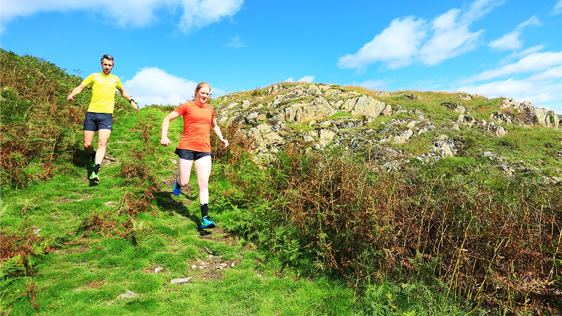 two runners run down a muddy trail