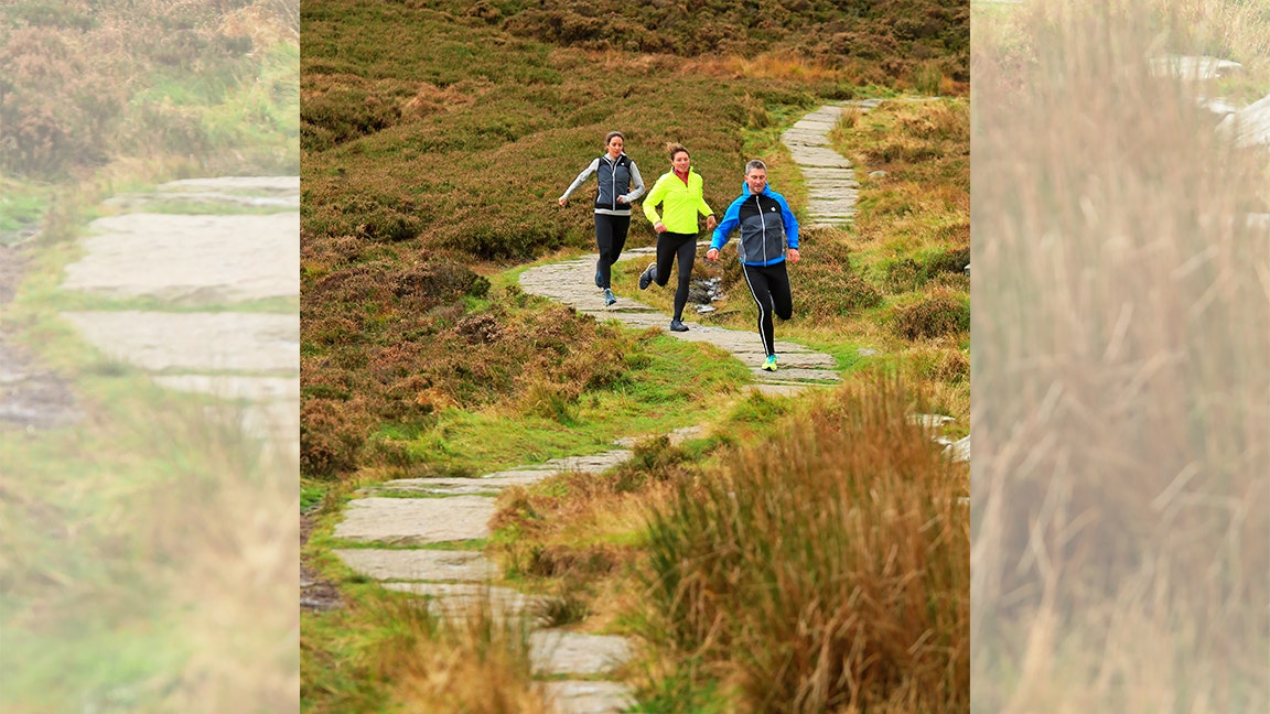 three runners run down some steps on a trail