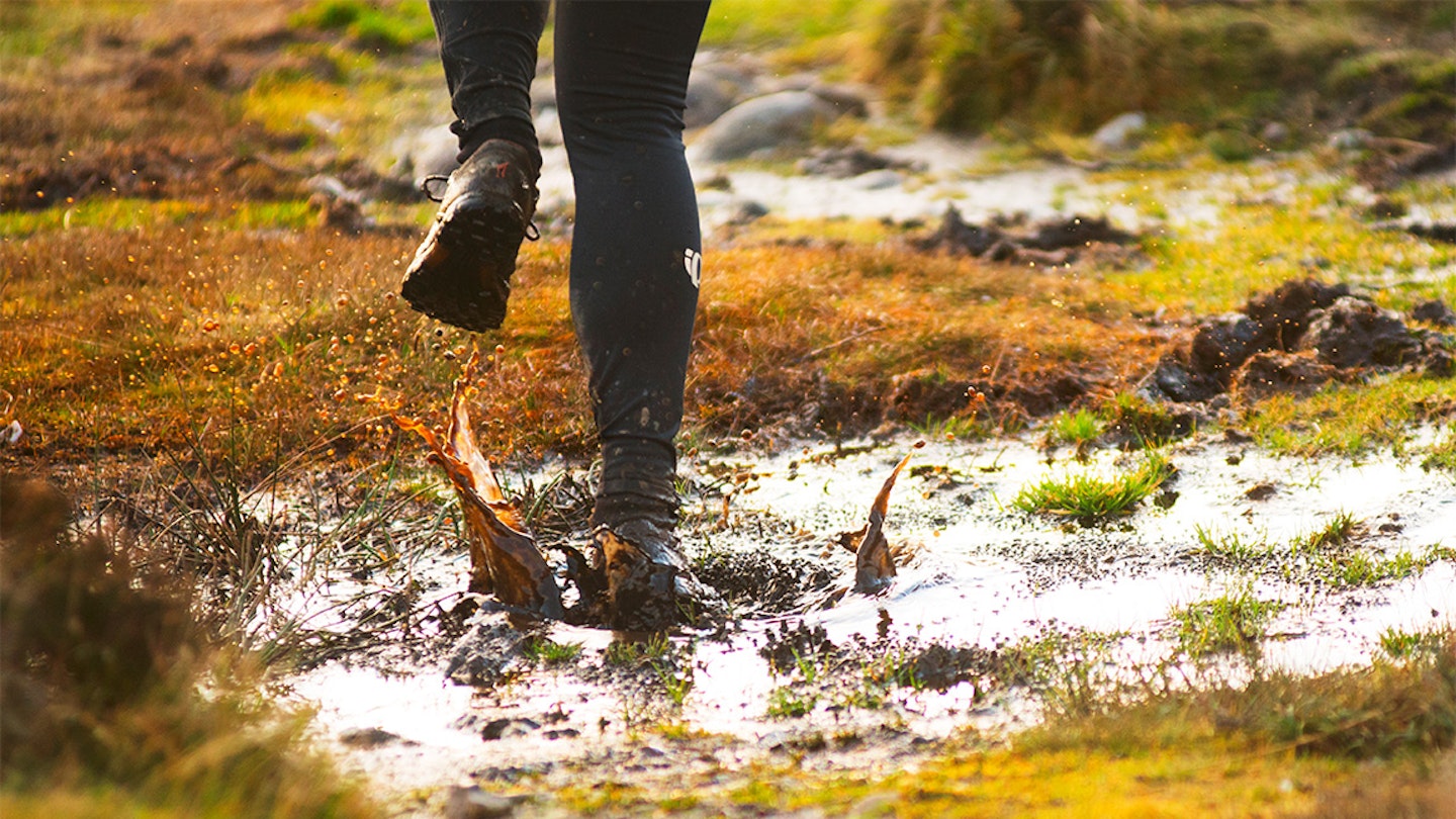 woman runs through muddy puddle