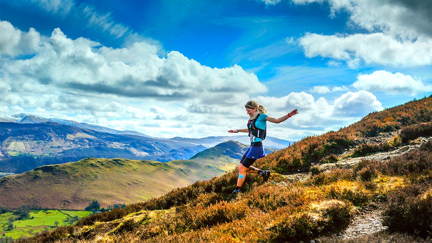 woman runs down a hill in the mountains