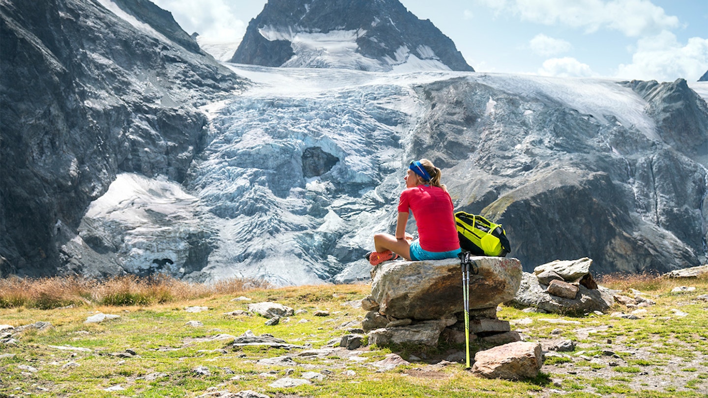 woman sits on a rock to enjoy the view of mountains