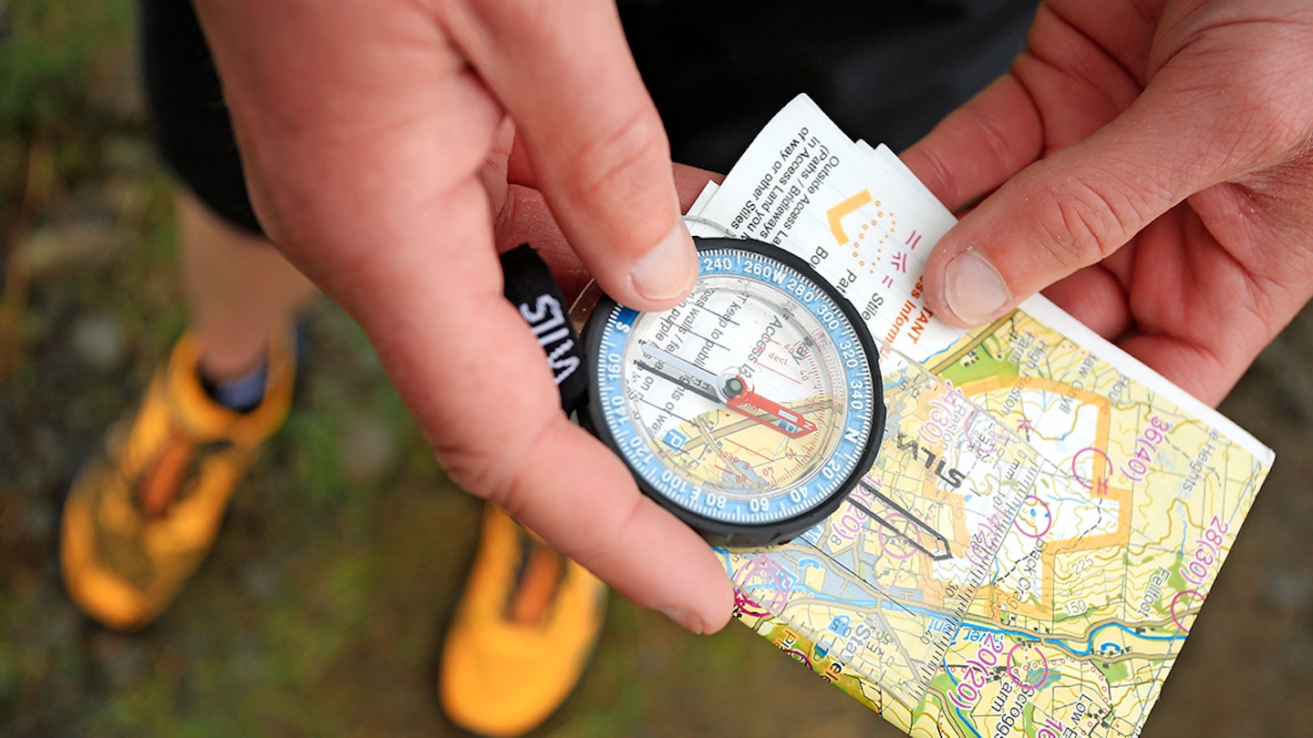 trail runner looks at a map with a compass