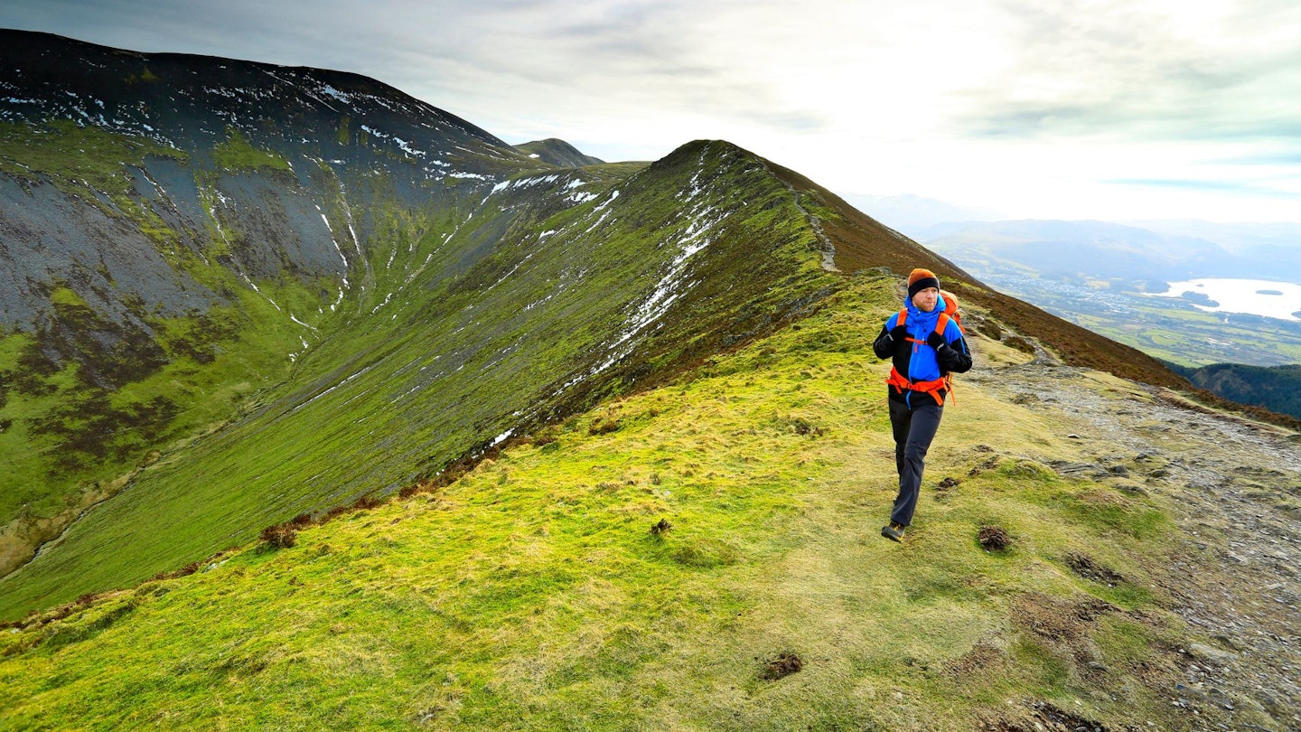 Hiker walking along Longside Edge, Lake District in winter
