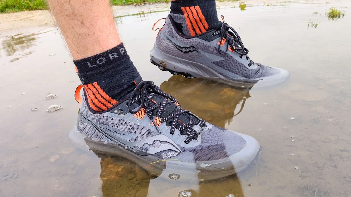 Runner wearing Saucony Peregrine 13 GTX waterproof trail running shoes standing in a puddle