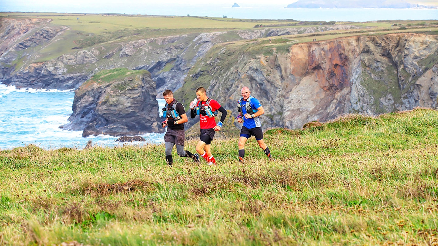 three runners run along cliff top in cornwall