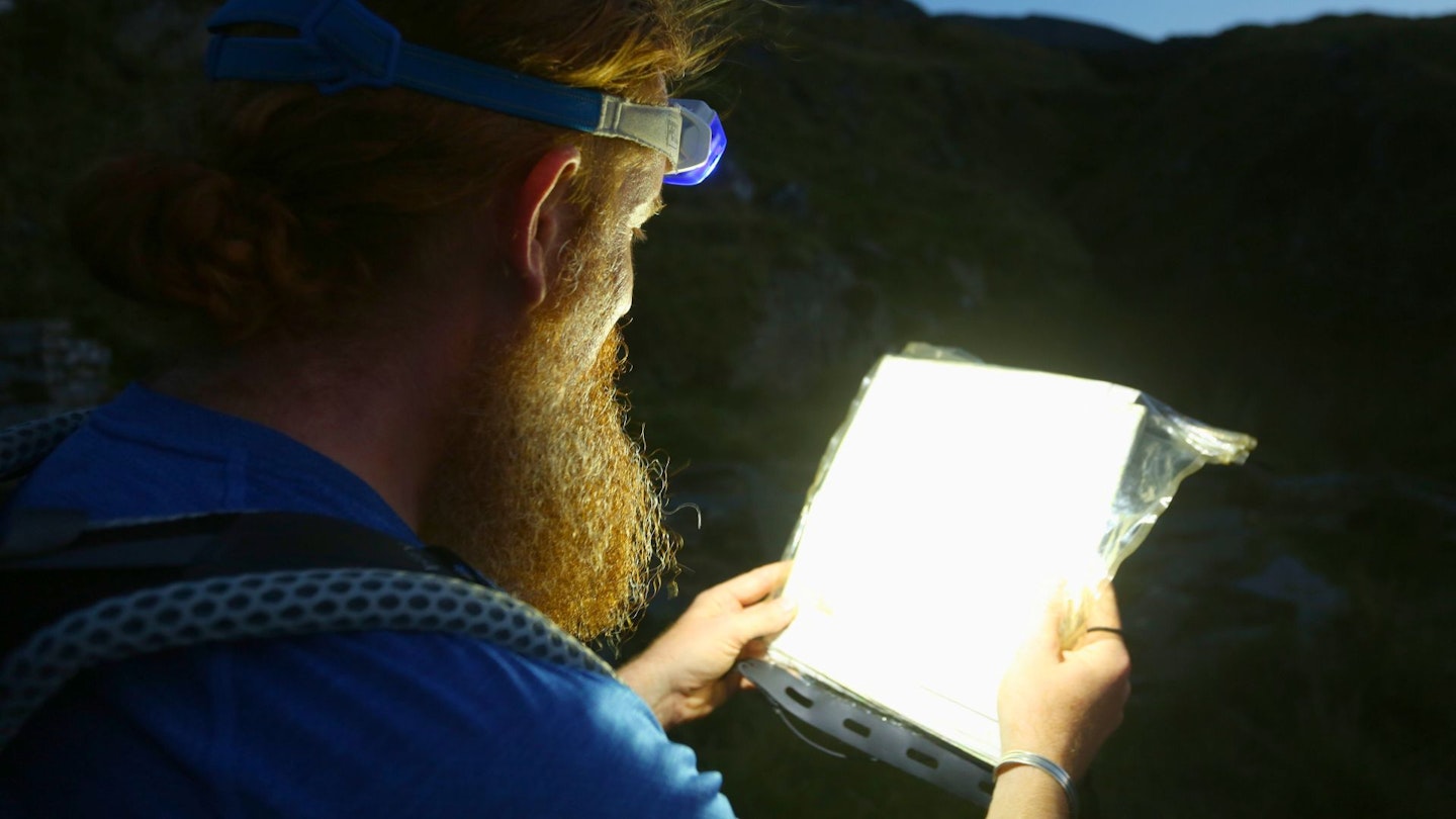 Hiker reading a map at night while wearing a head torch