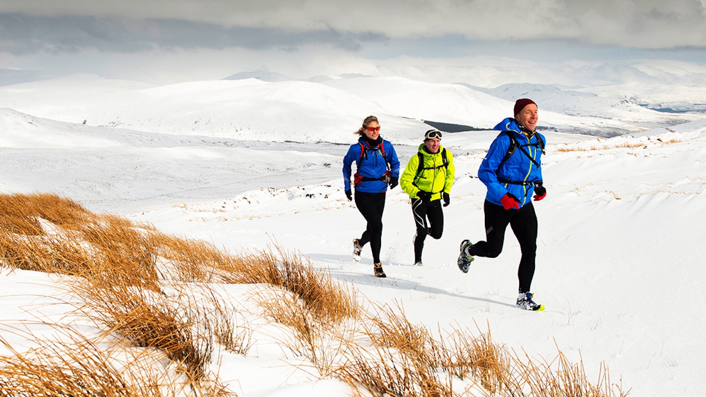 three runners run across the snow