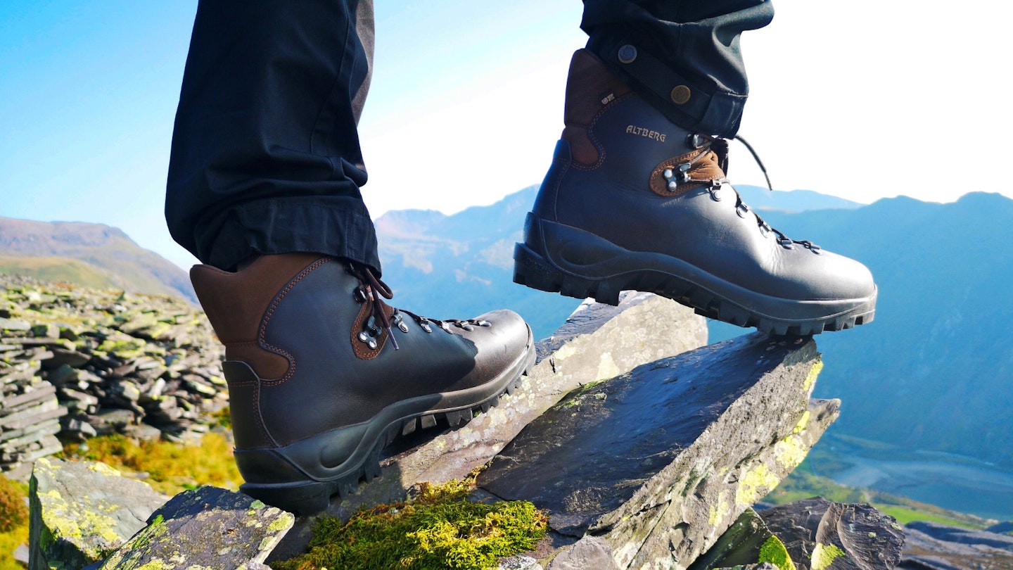 A hiker standing on a rock, wearing leather walking boots